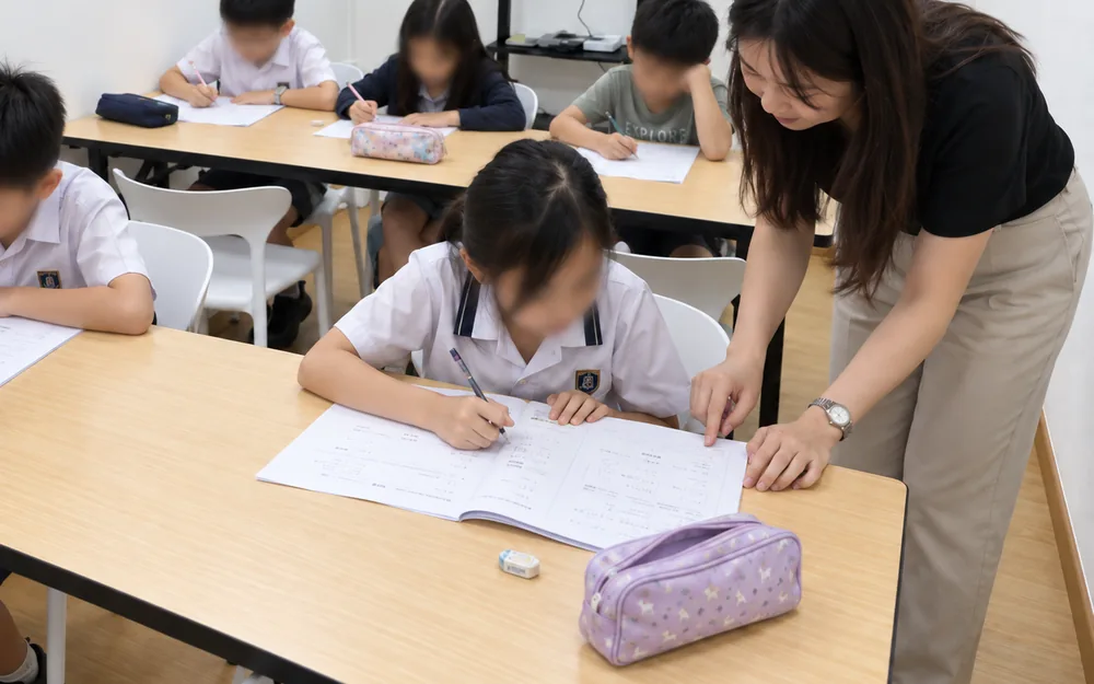 Primary Maths lesson at WhaleYou Learning with the teacher checking a student's work